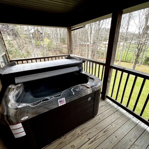 Ein Whirlpool auf einer Holzterrasse mit Blick auf ein bewaldetes Gebiet.