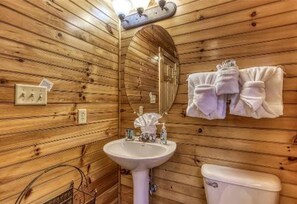 A wooden-paneled bathroom with a sink, toilet, and towel rack. - Dreams Come True With This Luxury Cabin (Gatlinburg)
