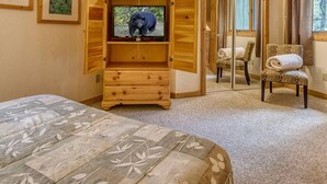 Une pièce comprenant un lit, une armoire en bois avec un téléviseur, une chaise et un miroir.