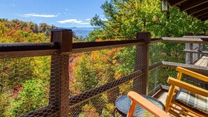 Eine Holzterrasse mit Blick auf Herbstlaub und Berge.