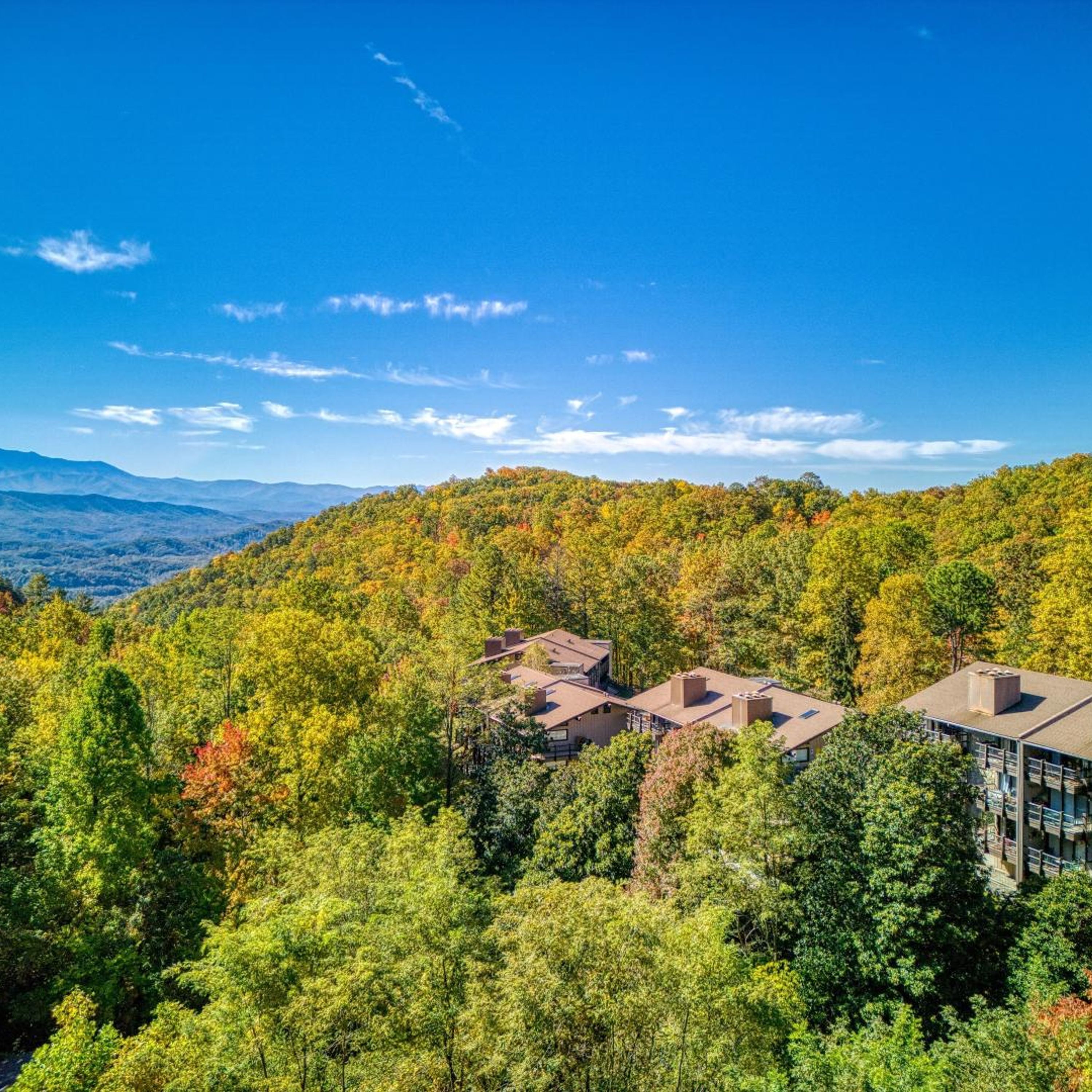 Un bâtiment moderne doté de plusieurs toits, situé au cœur d’une région montagneuse et boisée.