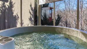 A hot tub in a room with large windows, a view of trees and a building outside. - Irresistible Retreat w Pool Hot Tub Arcade (Sevierville)