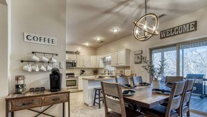 A kitchen with a wooden table, chairs, a coffee station, and a 'Welcome' sign. - Irresistible Retreat w Pool Hot Tub Arcade (Sevierville)
