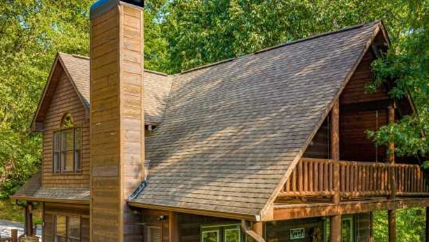 Une cabane en bois avec un balcon et une cheminée.