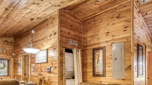 A cozy cabin interior with a wooden interior, a sofa, a coffee table, and a dining area. - Dog Friendly Romantic Mtn Getaway Hot Tub Pool (Gatlinburg)