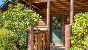 A wooden cabin with a porch, a green door, and a number plate. - Dog Friendly Romantic Mtn Getaway Hot Tub Pool (Gatlinburg)