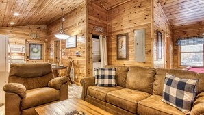A cozy cabin interior with a wooden ceiling, a sofa, a chair, and a dining table. - Dog Friendly Romantic Mtn Getaway Hot Tub Pool (Gatlinburg)