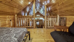 Ein rustikales Blockhaus mit hohen Decken, Holzwänden, einem Bett, einer Couch und einem Essbereich.