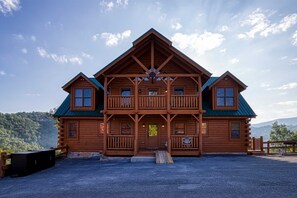 A two-story log cabin with a balcony, a front porch, and a sign indicating the address. - Prestigious Luxury Pool Game Room Mtn Views (Sevierville)