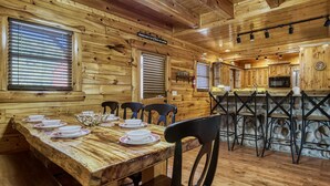 Ein Holzblockhaus-Interieur mit Essbereich, Küche und Bar.