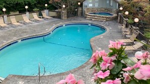 Une piscine avec des chaises longues et, en arrière-plan, un bâtiment en pierre.