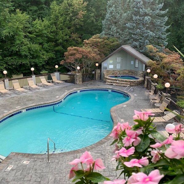 A swimming pool with lounge chairs and a stone building in the background.
