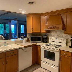 A kitchen with wooden cabinets, a microwave, a stove, and a dishwasher.