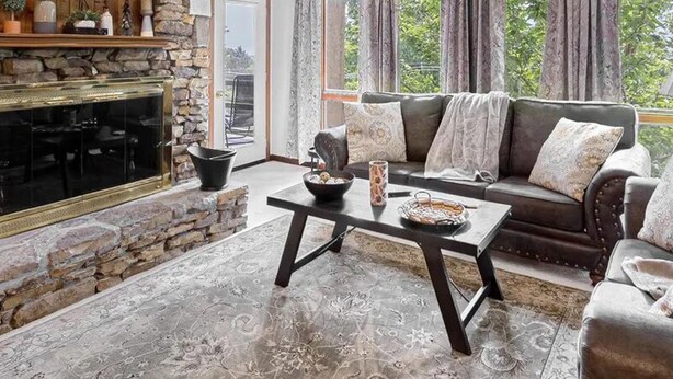 Un salon avec une cheminée en pierre, un téléviseur fixé au mur, un canapé et une table basse.