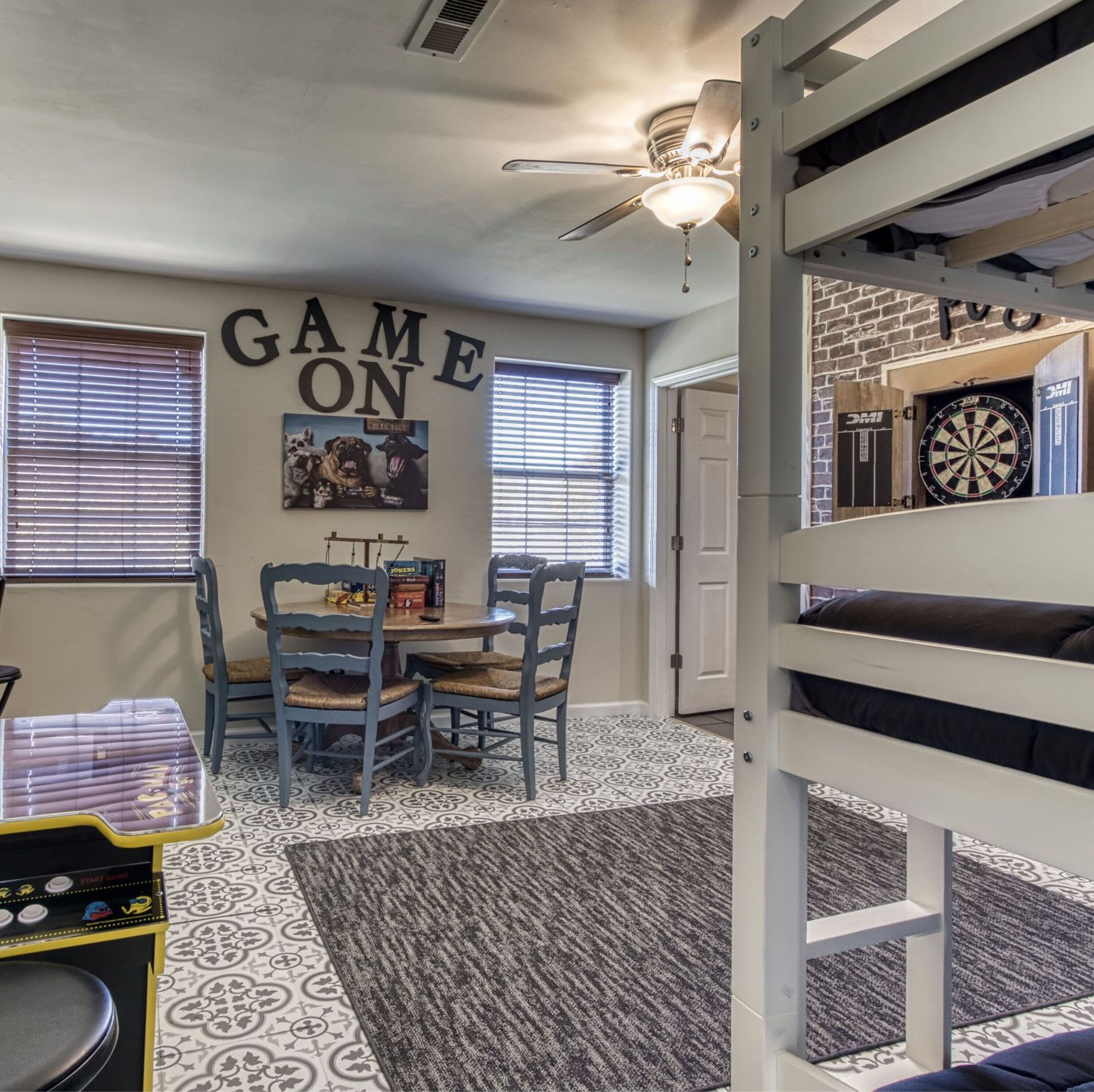 Ein Zimmer mit Deckenventilator, Dartscheibe und Wand mit dem Schriftzug 'GAME ON'.