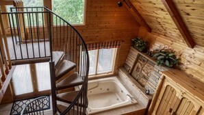 Ein Holzblockbau-Innenraum mit Wendeltreppe, Badewanne und Holzschrank.