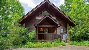 Eine Blockhütte mit Steinunterbau, einer Holzveranda und einem Satteldach.
