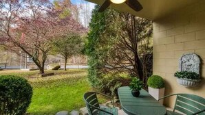 Un patio con tavolo e sedie, circondato dal verde e da un muro in mattoni.