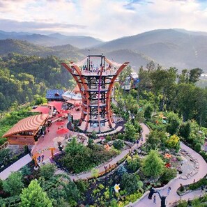 A large, multi-level structure with a spiral staircase, surrounded by lush greenery and a winding path.