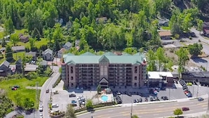A large hotel with a green roof, surrounded by lush greenery and hills. - Luxurious Condo Pool Fireplace Hiking (Gatlinburg)