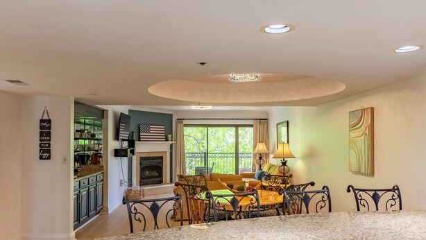 A kitchen with a granite countertop, white cabinetry, and a dining area with a table and chairs. - Luxurious Condo Pool Fireplace Hiking (Gatlinburg)
