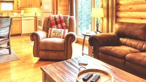A cabin interior with a wooden interior, a dining area, a sofa, and a coffee table. - Cozy Upscale Cabin w Fireplace Hot Tub (Sevierville)