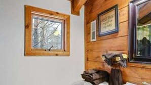 A wooden cabin bathroom with a toilet, sink, and a framed picture on the wall. - A Charming Cabin Pool Firepit Hot Tub-jacuzzi (Gatlinburg)