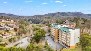 Un hotel a più piani con tetto verde, immerso in un paesaggio collinare e circondato da edifici residenziali.