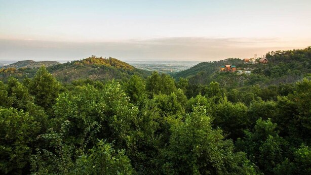 Eine gebirgige Landschaft mit üppigem Grün und einigen Gebäuden auf den Hügeln.