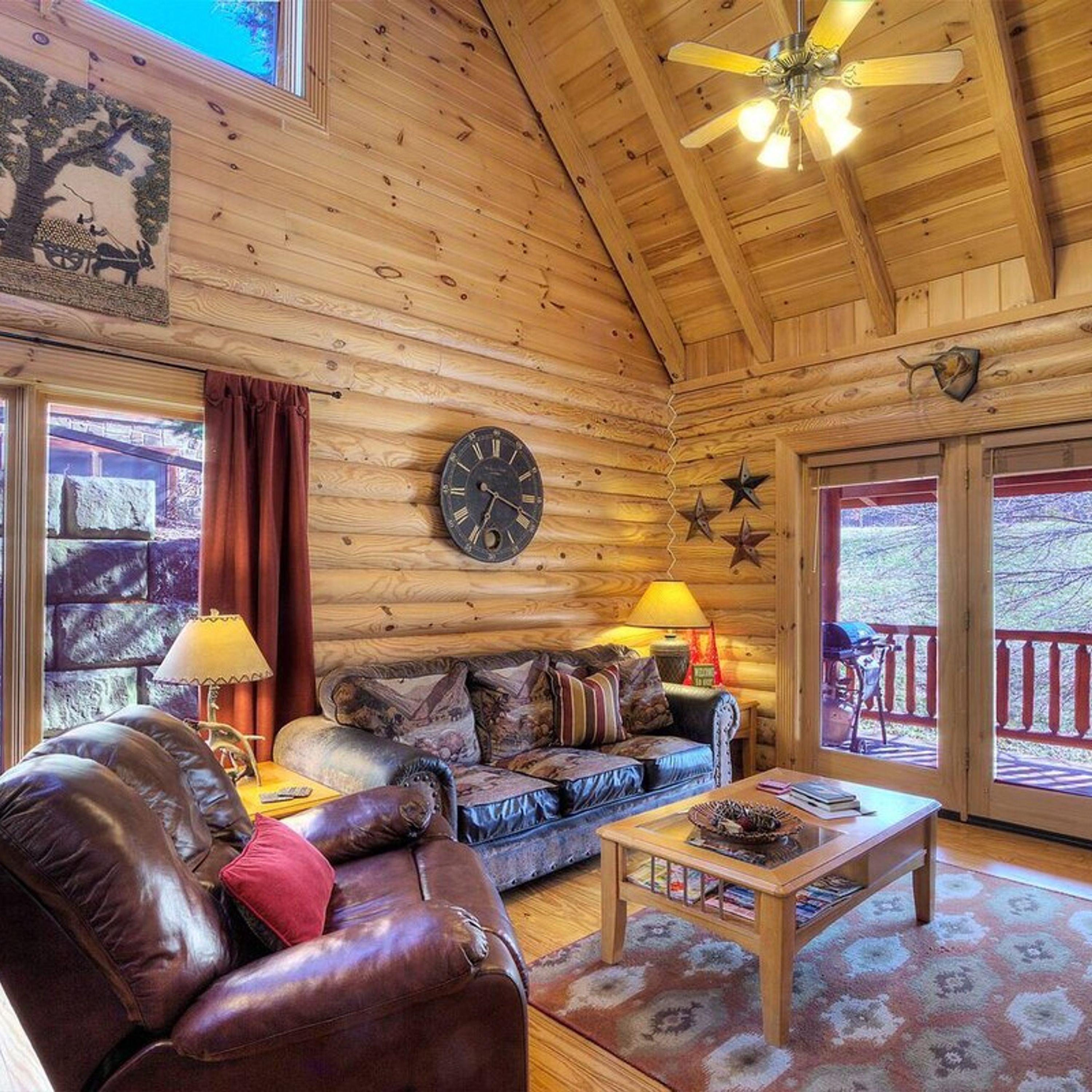 A cozy log cabin interior with a leather sofa, a wooden coffee table, and a wall clock.