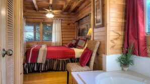 Interior de una cabaña de madera con un dormitorio, baño y sala de estar.