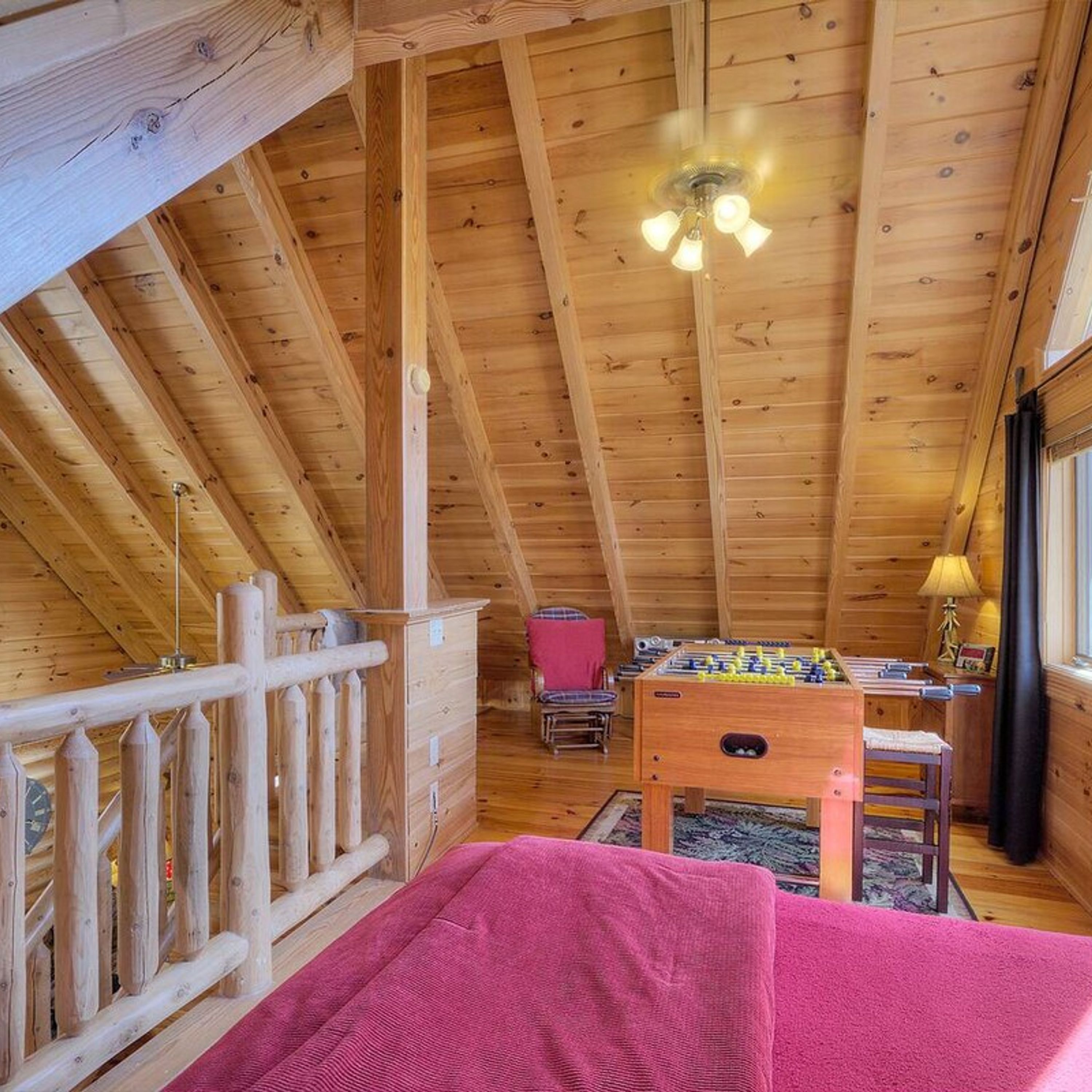 Une charmante cabane en bois avec une chambre à coucher en mezzanine, une table de baby-foot et un coin repas.