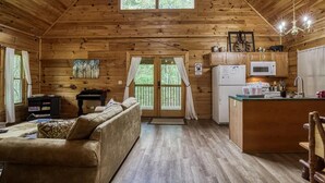 A cozy cabin interior with a wooden interior, a sofa, a dining table, and a kitchen area.
