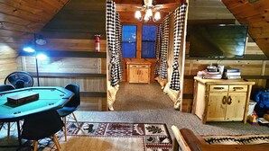 A cozy attic room with a wooden ceiling, a ceiling fan, a table with chairs, a rug, and a small cabinet. - 5-star w Pool Cozy Secluded Newly-renovated (Sevierville)