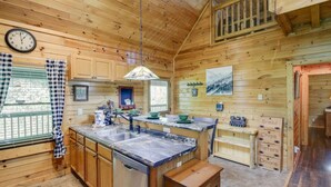 A wooden cabin kitchen with a central island, wooden cabinets, a clock, and a window with checkered curtains. - 5-star w Pool Cozy Secluded Newly-renovated (Sevierville)