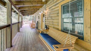 A wooden cabin with a porch, a swing, and a large window. - 5-star w Pool Cozy Secluded Newly-renovated (Sevierville)
