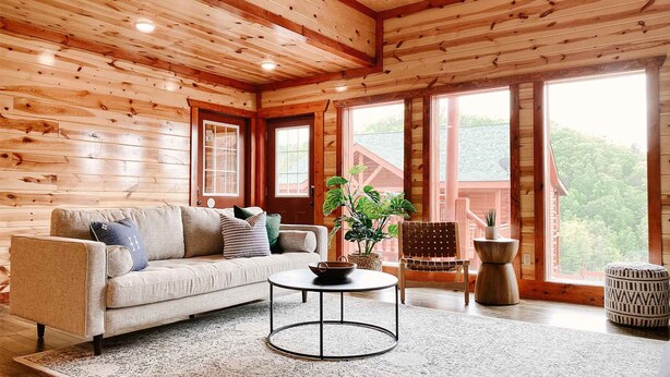 A cozy cabin interior with a sofa, a round coffee table, and a chair. - Modern Luxury w Pool Theater Hot Tub Ent Room (Sevierville)