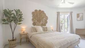 Une chambre à coucher avec un lit, des lampes de chevet, une œuvre d’art murale et une fenêtre avec des rideaux.