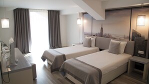 A hotel room with two beds, a desk, and a cityscape mural on the wall.