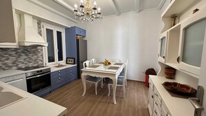 Une cuisine moderne avec un coin repas, comprenant un lustre, des placards et un réfrigérateur.