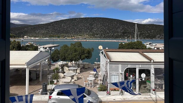 Une vue sur la côte, avec une montagne, un port de plaisance et un bâtiment doté d’une terrasse.