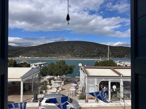 Vista costera con montaña, puerto deportivo y un edificio con terraza.