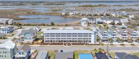A residential area with houses and a large building, likely a hotel, with a view of a water body in the background.