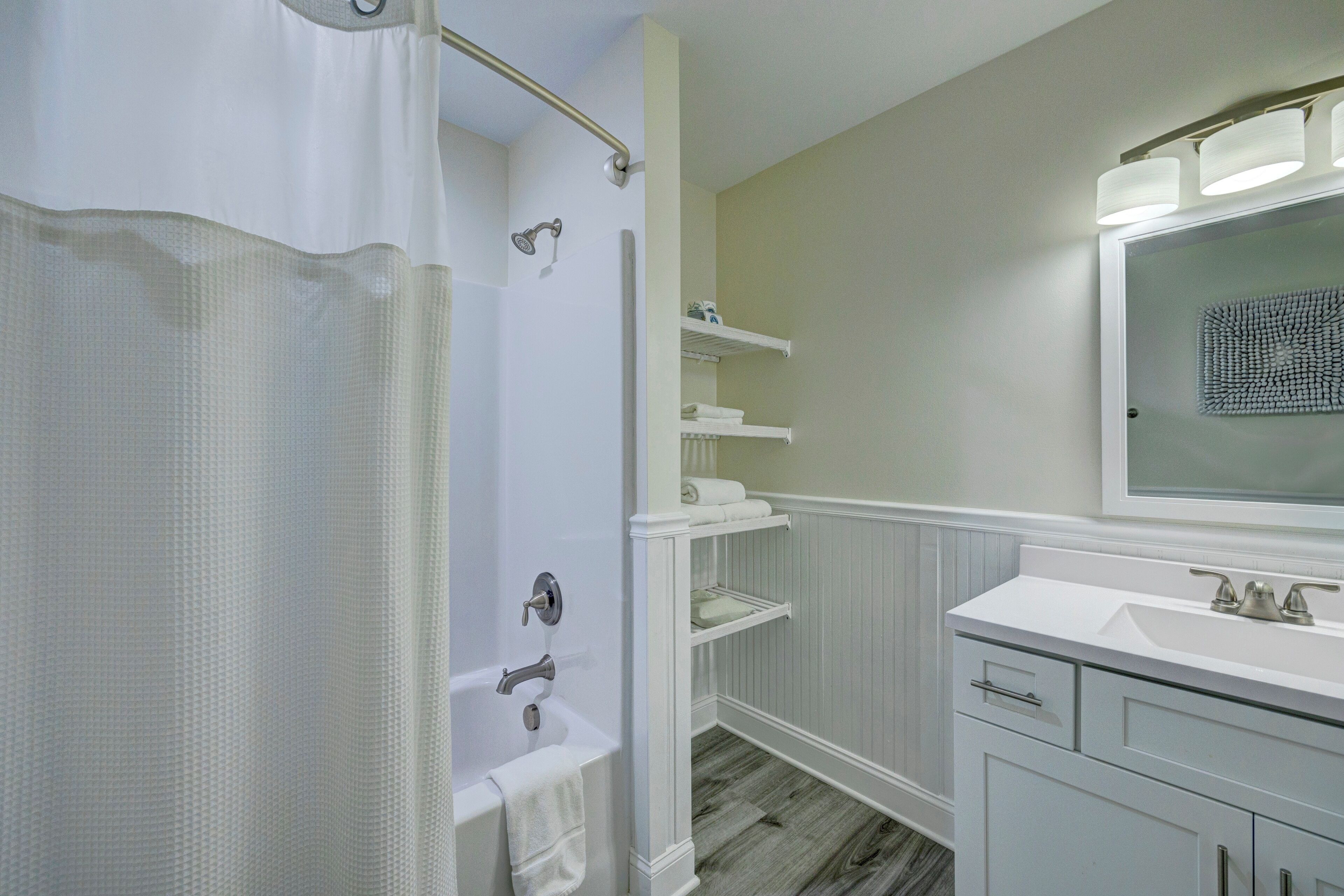 A bathroom with a shower, a sink, and a mirror.