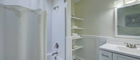 A bathroom with a shower, a sink, and a mirror.