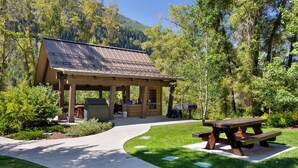 A covered picnic area with a grill, picnic table, and a paved walkway. - Charming and Upgraded 3 Bedroom Mountain Townhome by Gorecreek Rentals (Vail)