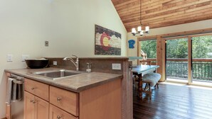 A kitchen with wooden cabinets, a granite countertop, a double sink, and a large window overlooking a deck. - Charming and Upgraded 3 Bedroom Mountain Townhome by Gorecreek Rentals (Vail)