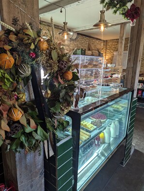 A bakery display case with various baked goods and a decorative wall with seasonal decorations. - The Duke Hotel (Calne)