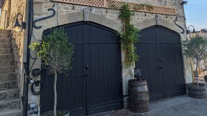 Ein Steinhaus mit einem Schild, auf dem 'The Coach House' steht. Es hat zwei schwarze Doppeltüren, ein kleines Fenster mit Diamantmuster und ein hölzernes Gitterwerk über den Türen.