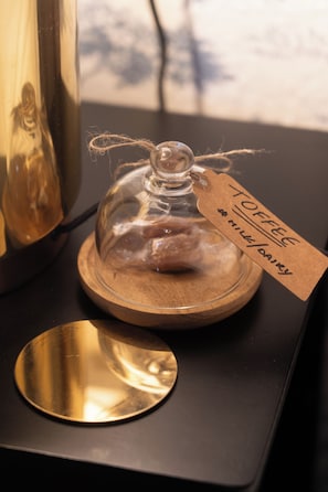 A glass dome with a tag labeled 'TOFFEE' on a wooden surface. - The Duke Hotel (Calne)